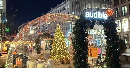 Die begehbare Audible-Schneekugel auf dem Düsseldorfer Weihnachtsmarkt in der Schadow-Straße lädt Familien und Fans zur gemeinsamen Entdeckungsreise durch kuratierte Hörgeschichten ein (Quelle: Audible / Wavemaker)