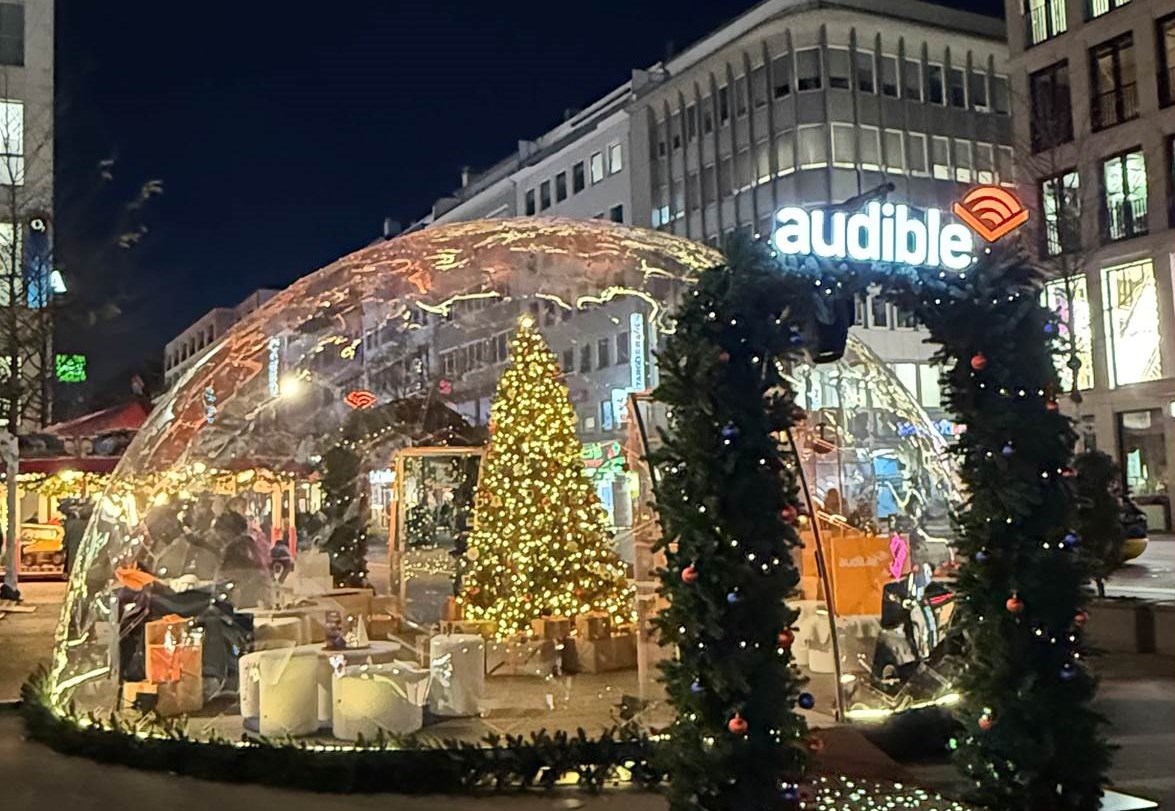 Die begehbare Audible-Schneekugel auf dem Düsseldorfer Weihnachtsmarkt in der Schadow-Straße lädt Familien und Fans zur gemeinsamen Entdeckungsreise durch kuratierte Hörgeschichten ein (Quelle: Audible / Wavemaker)